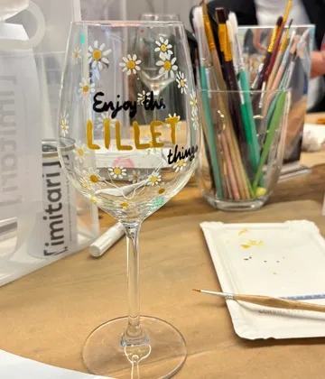 Wine glass with daisies on a table.