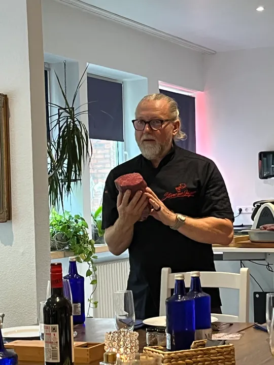 Man holding meat in dining room.