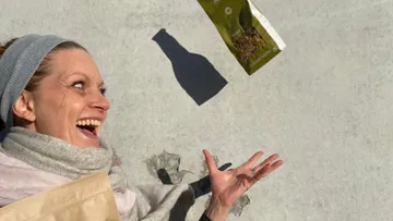 Woman joyfully tosses snack bag outdoors.