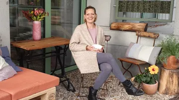 Woman sitting on patio holding a cup.