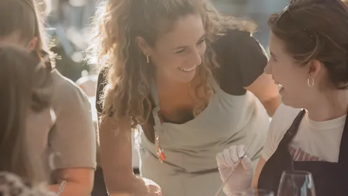 Woman smiling with friend at outdoor event.