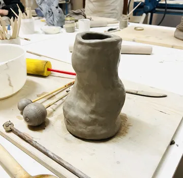 Clay pot being shaped on worktable.