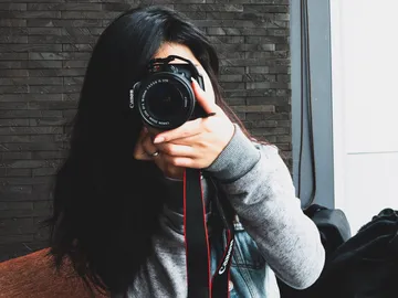 A person holds a camera and takes pictures in a room.
