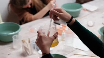 Hands stirring liquid in a beaker.