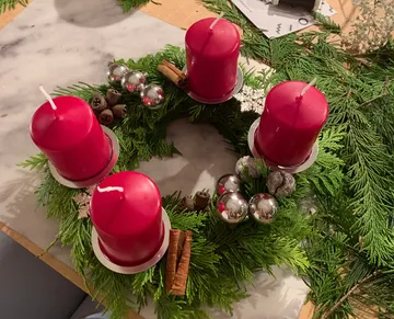 Adventskranz mit roten Kerzen auf Tisch.