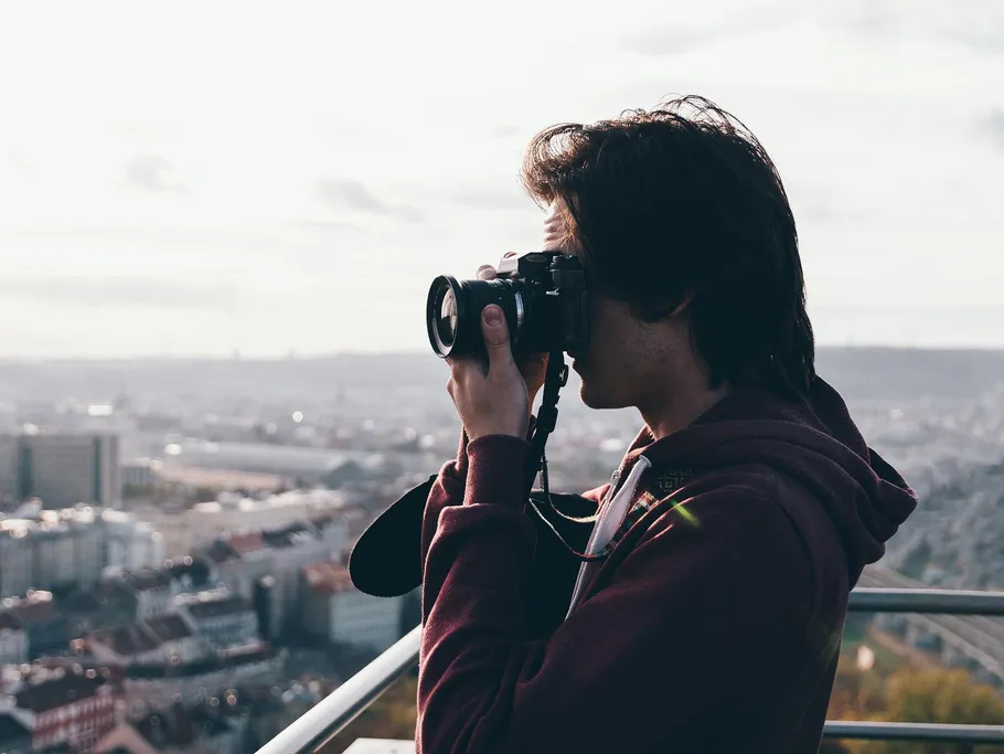 Young man takes pictures of a city view from an observation deck.