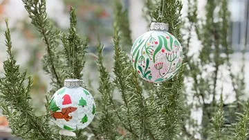 Ornamente hängen an Kiefernzweigen draußen.