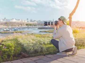 Person taking pictures of landscape with camera outdoors.