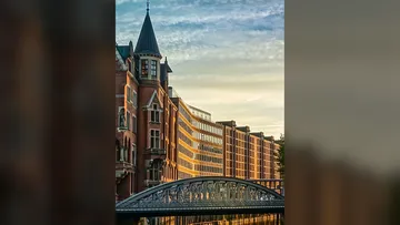 Historic building beside bridge at sunset.