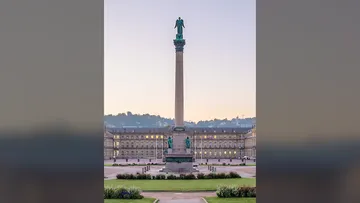 Hohe Säule auf großem Stadtplatz.