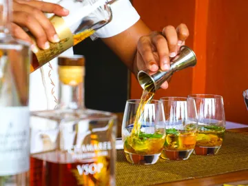 A bartender pours drinks into glasses at a bar.