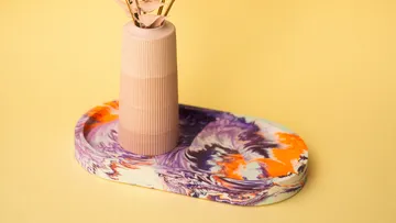 Vase with dried flowers on colorful tray.