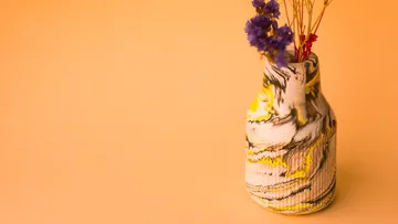 Colorful vase with flowers on orange background.