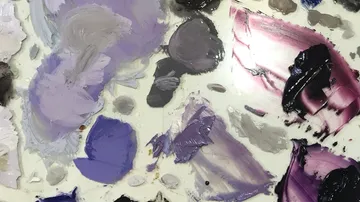 Colorful paint blobs on artist's palette.