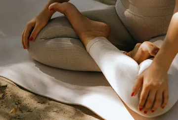 Person sitzt in Yoga-Pose im Freien.