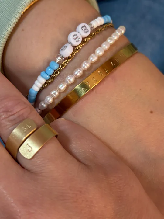 Armbänder und Ringe an einem Handgelenk.