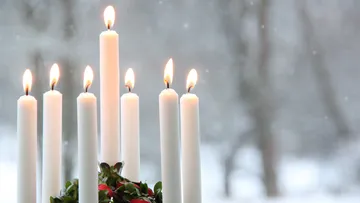 Candles burning in snowy window background.