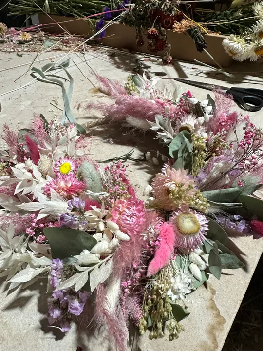 Floral wreath with pink and white flowers on table.