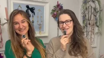 Two women smiling, holding microphones indoors.