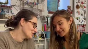 Two women smiling, crafting indoors.