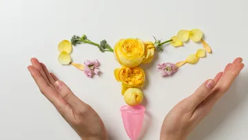 Blumen und Becher formen Uterus auf Weiß.