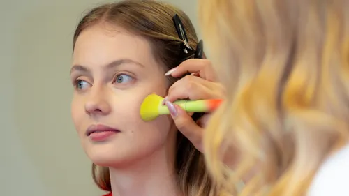 Woman's face being brushed during makeup session.