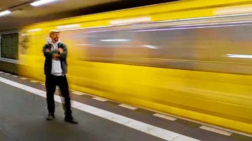 Man standing as yellow train speeds by