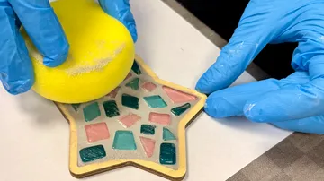 Hände reinigen sternförmiges Mosaikhandwerk.