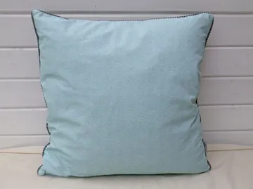 A light blue pillow on white panel wall.