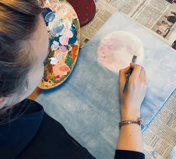 Eine Person malt einen großen Mond auf Papier.