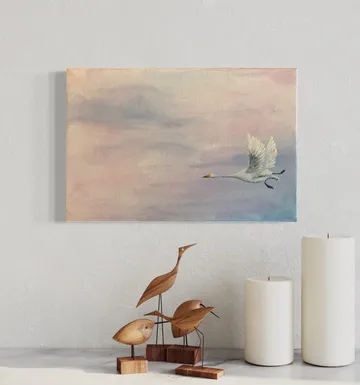 Ein Schwan fliegt vor einer sanften Himmelshorizont. Holzvögel und Kerzen sind im Vordergrund.