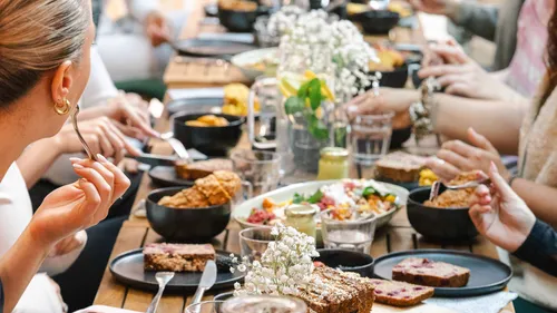 Menschen essen an einem langen Tisch im Freien.