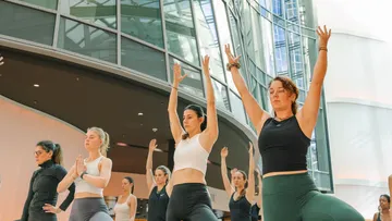 Women practicing yoga indoors, arms raised.