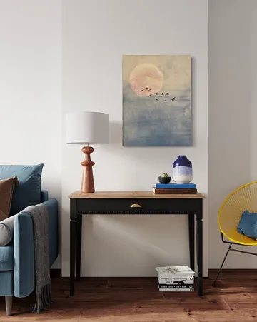 Wooden table with lamp, vases and pictures in a living room.