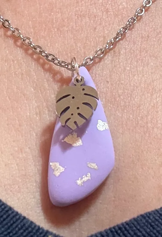 Lila Anhänger mit Blatt an Kette.