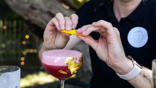 Hände bereiten Cocktail mit Zitronenschale zu.