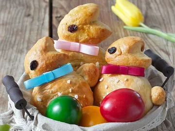 Dough breads in a basket with colorful eggs.