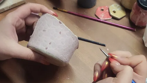 Hände bemalen Keramikbecher auf Tisch.