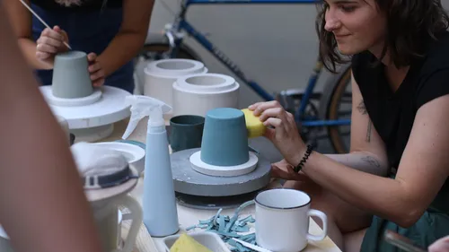 Person painting ceramics outdoors at table.