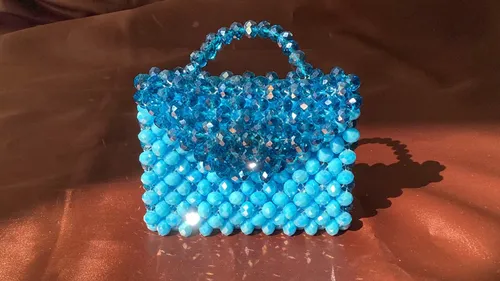 Blue beaded handbag on brown surface.