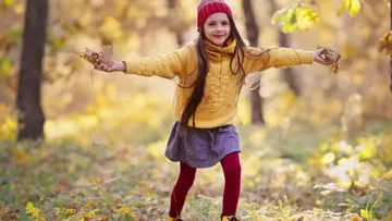Mädchen spielt mit Blättern im Wald.