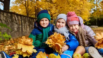 Drei Kinder halten Blätter im Herbstpark.
