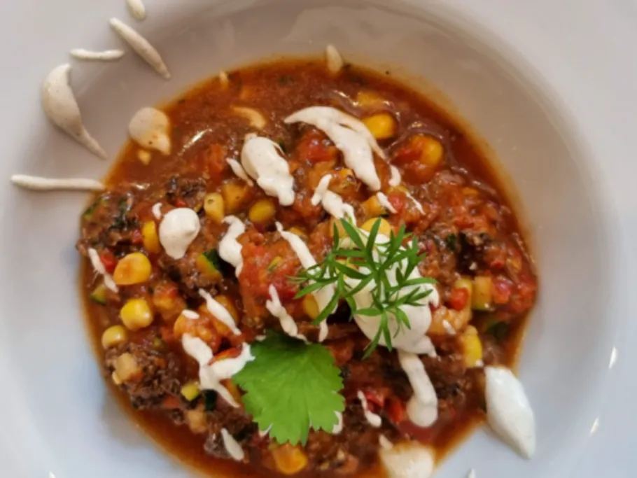 Bunte Suppe mit Gemüse und frischem Korianderserviert.