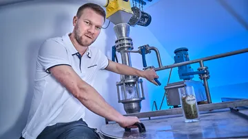 Man operating industrial machine indoors.