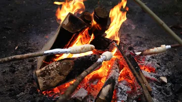 Brot auf Stöcken über Lagerfeuer geröstet.