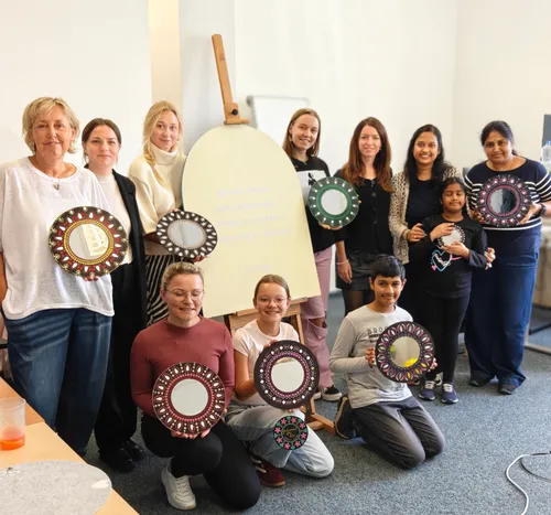 Group holding painted mirrors indoors.