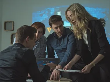 People analyse documents together in a meeting room.