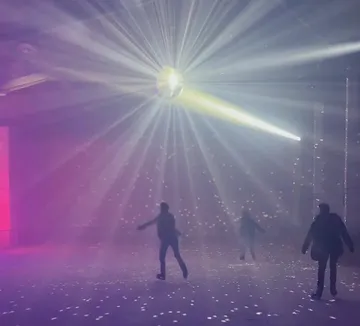 Menschen auf Schlittschuhen im Disco-Licht.
