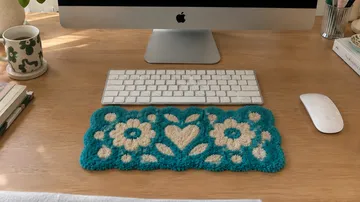 Gestrickte Blumenmatte auf Holztisch.