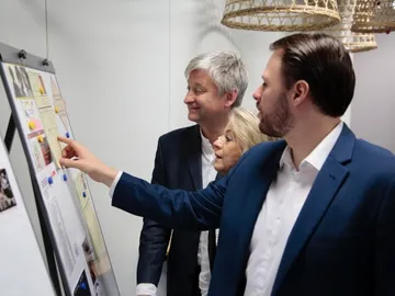 Three people look at information together on a flip chart.